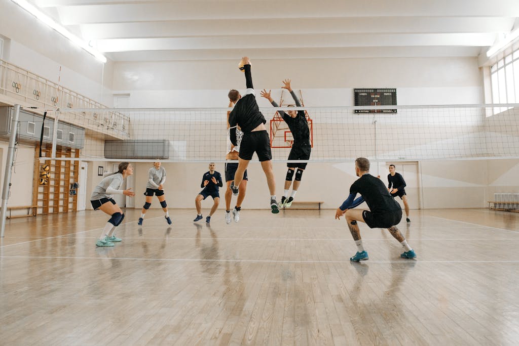 Men and women engaged in a competitive indoor volleyball match, showcasing teamwork and athleticism.